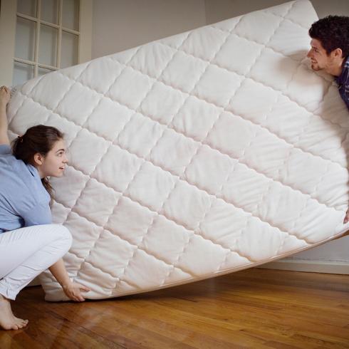 A couple turning over their mattress as a part of cleaning your mattress