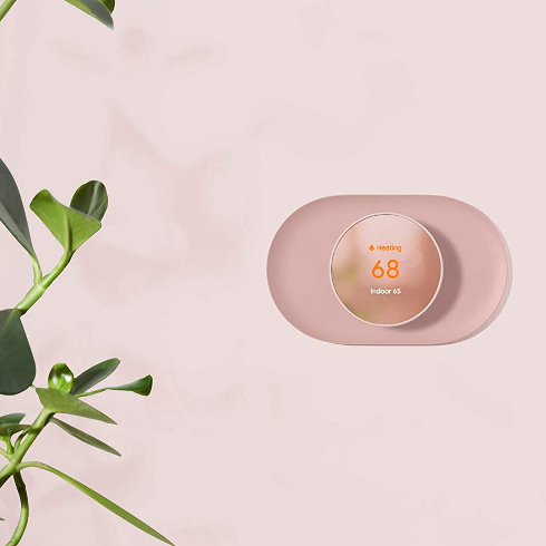 The Google Nest Thermostat in a stylish pink room with plant