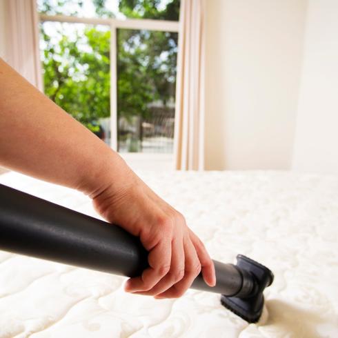 Person vacuuming their mattress without any sheets