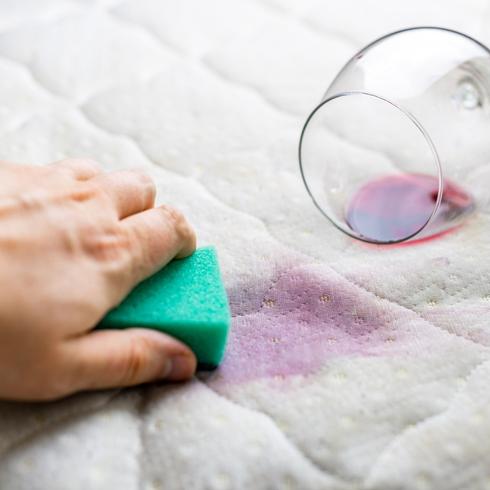 Person cleaning red wine stains off mattress