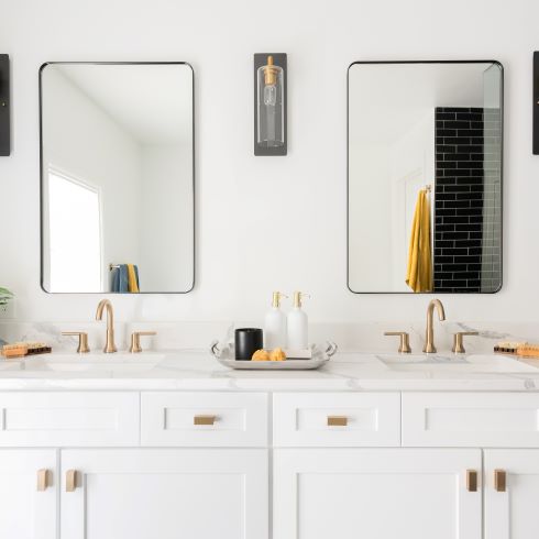 Twin vanities with white cabinetry and gold fixtures