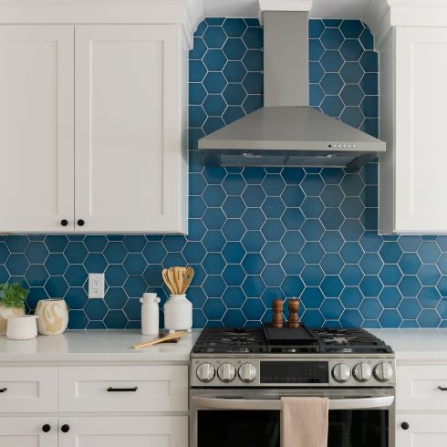 White kitchen cabinets, blue tile backsplash, and stainless steel range hood.