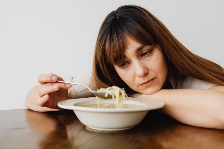 Unhappy woman eating a bowl of soup at home - Toronto food bank crisis 