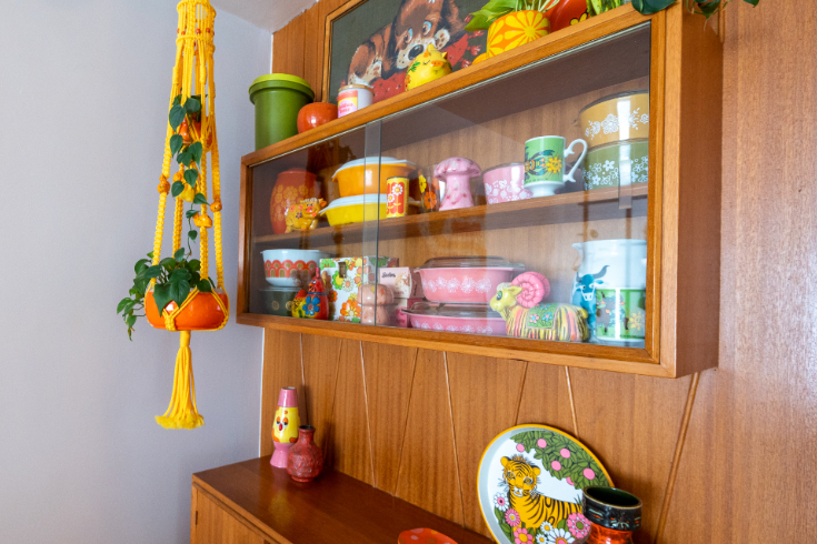 The wooden hutch in the dining area, filled with vibrant ceramics