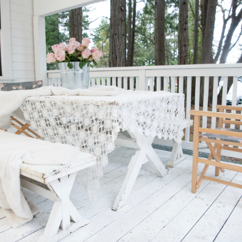 The exterior porch of The Cabin with a white picnic bench, roses on the table