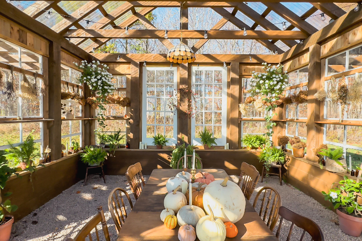 The dining table and mismatched wooden chairs inside the greenhouse on the A-Frame property