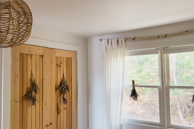 The wooden closet door and birch branch curtain rod in the primary bedroom