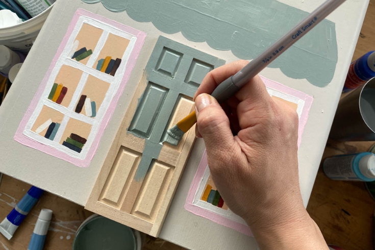 A person painting a door in their DIY doll house nightstand project