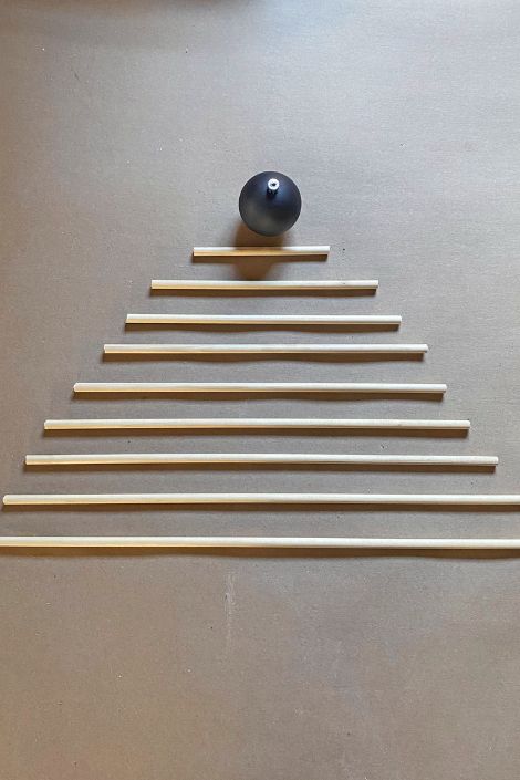 Wooden dowels laid out in a triangle alongside a black ornament 