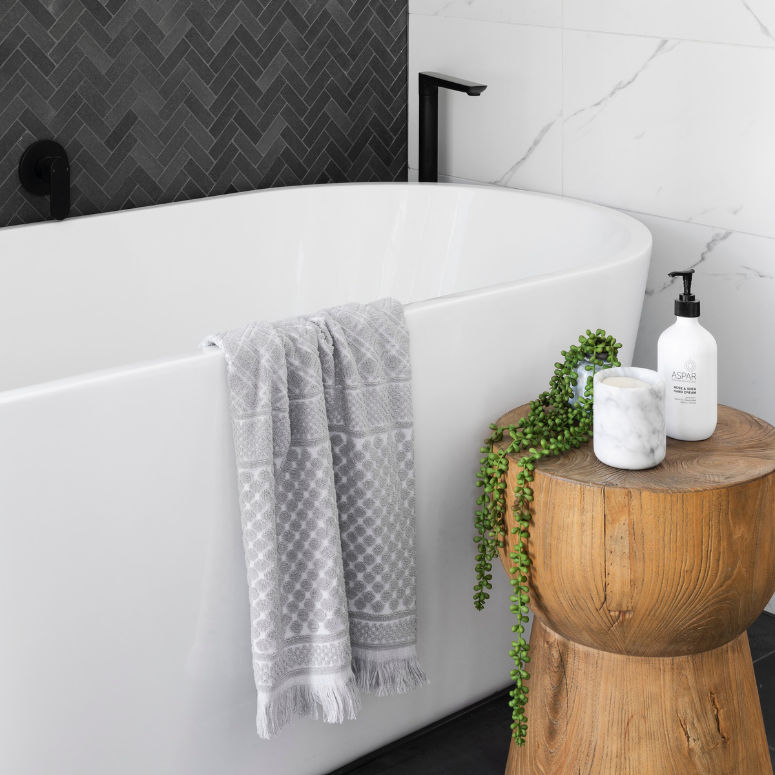 White bath tub with a wooden stool for spa products