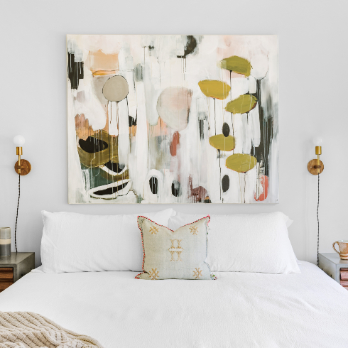 An oversized botanical painting above a bed with white linens