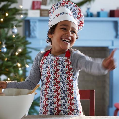 A kid wearing an apron and chef's hat