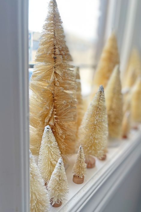Wooden dowel Christmas trees painted gold by a window