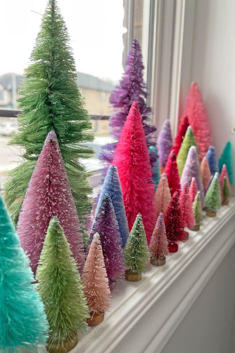 Multi-coloured artifical christmas trees by the window