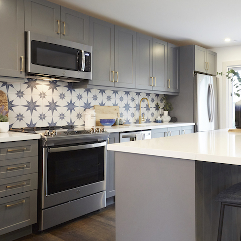 A beautiful kitchen for HGTV Canada’s Scott’s Vacation House Rules features grey cabinets and blue star patterned tile backsplash