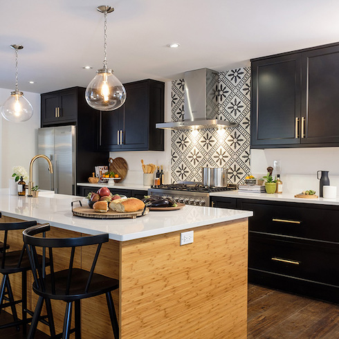 A designer kitchen with a classic black and white palette, from the semi-gloss cabinets to the Quartz countertop, and a stunning graphic tile backsplash