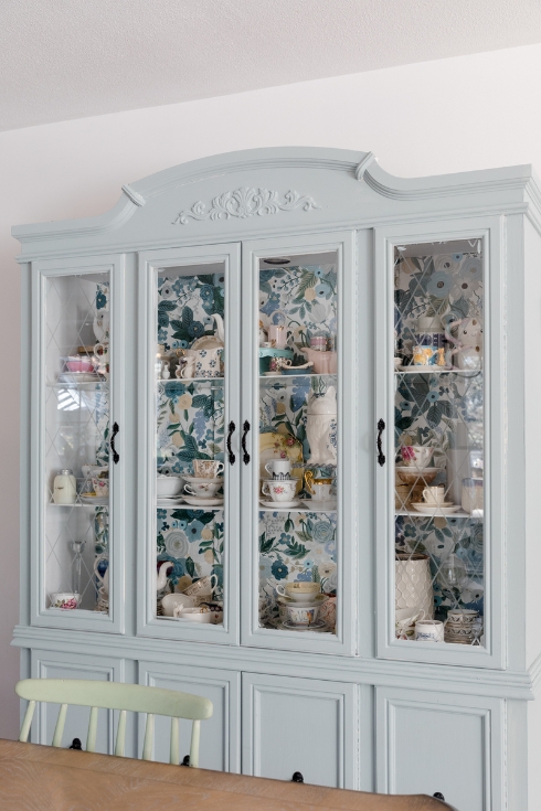 Blue vintage hutch with wallpaper.