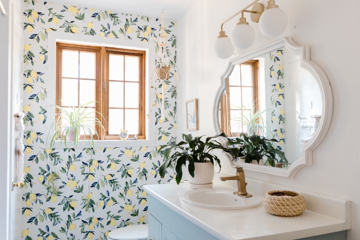 A blue and white bathroom with lemon printed wallpaper in a colourful Montreal home.