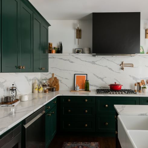 Rich green kitchen cabinets with matching white countertops and backsplash