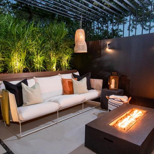 Trendy summer backyard with a white couch and modern firepit