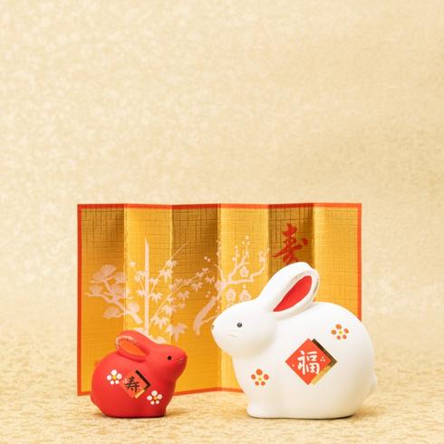 Two rabbits in front of a lunar new year decoration.