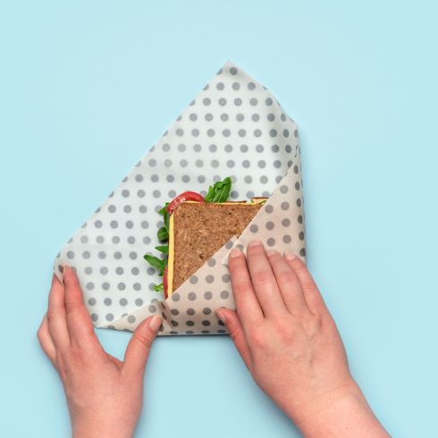 Person using beeswax wrap to fold sandwich