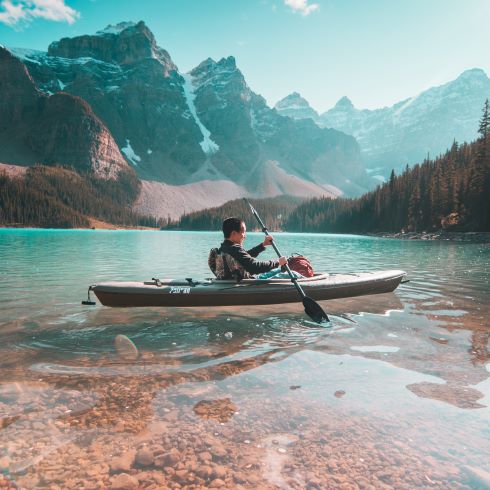 A kayaker on a lake with mountains in the background