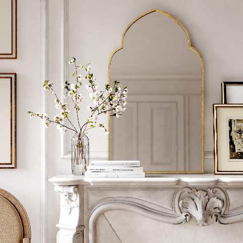 An arched mirror with a gold frame in a hallway