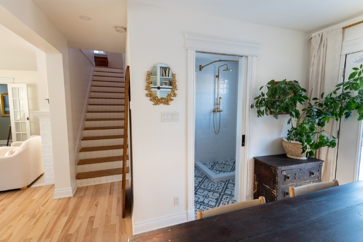 A staircase, bathroom entrance and part of a dining room with light-toned hardwood flooring