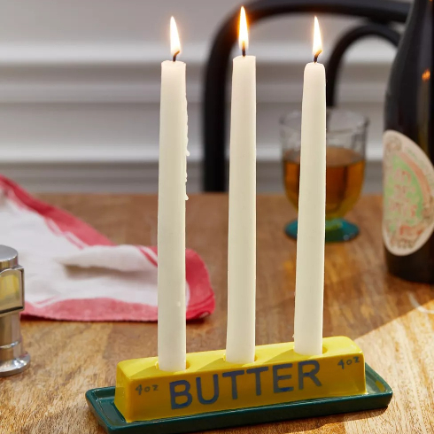 A butter-shaped candle holder with three long taper candles
