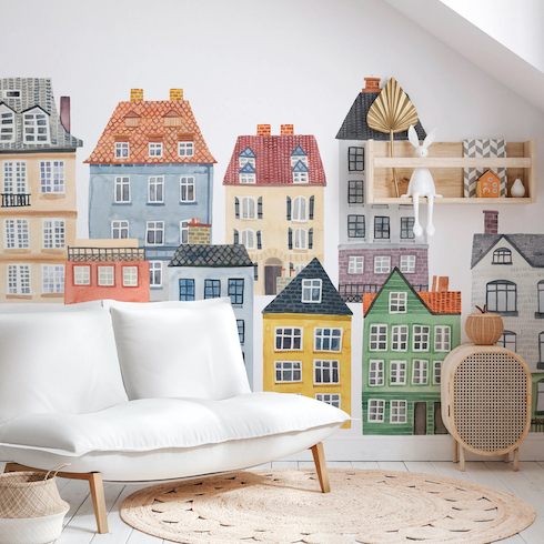 Set of repositionable Small Village Fabric Wall Decal Kit based on the streets of Copenhagen by Mej Mej with a low white sofa, round rattan run and wicker cabinet with an apple basket on top
