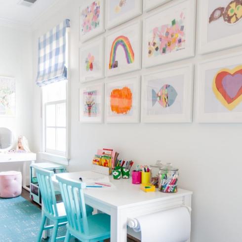 A white gallery wall displaying kids artwork