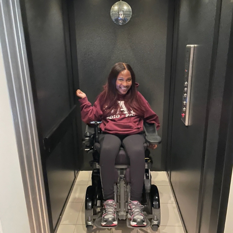 Person in a wheelchair, smiling in the elevator in her accessible home.
