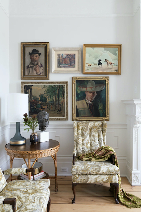 A chic living room designed by Cynthia Zamaria featuring antique charis and an art wall mixing modern and antique pieces