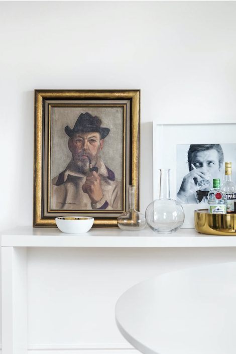A chic bar shelf designed by Cynthia Zamaria featuring a modern black and white photo portrait and an antique oil painting in a gold gilded frame