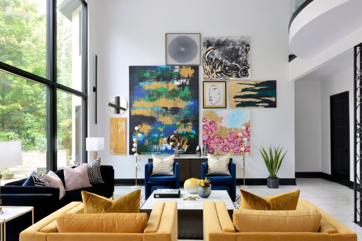 Colourful pieces of art in a living room. Two yellow couches and a black sofa. 