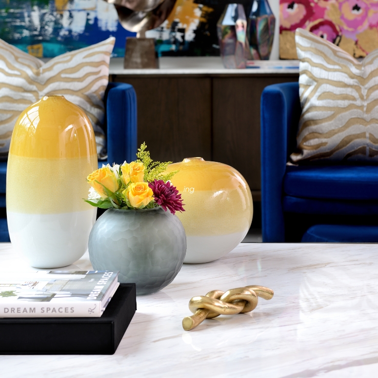 Two yellow vases, a bouquet of flowers and white coffee table.