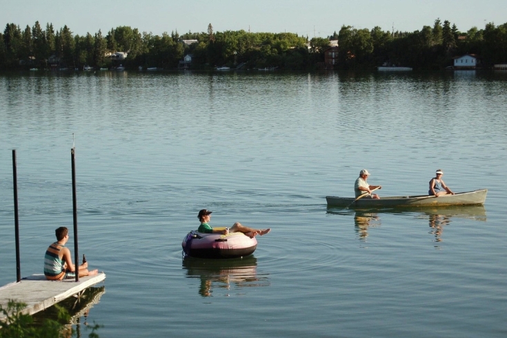 People swimming in a lake during the summer. 