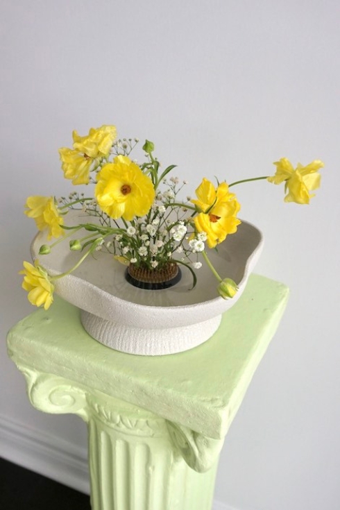 Yellow flowers on top of a beige Virdi plant stand and green table