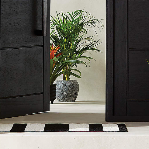 A black and white vertical striped front door mat in front of a modern entryway
