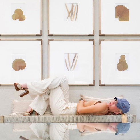 Gayle Alix lays on a shelf under framed simple white artwork