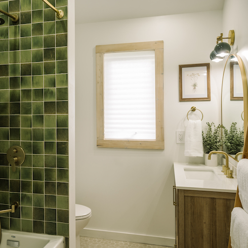 Green shower tiles in bathroom with wood finishes