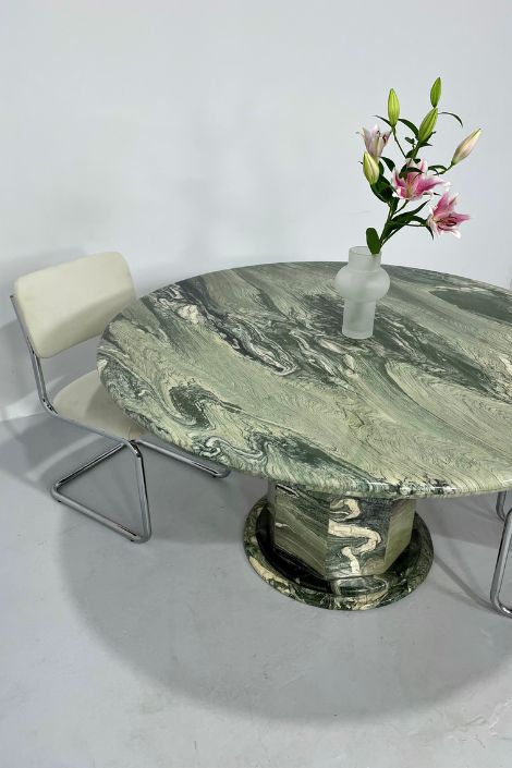 Large Italian marble table with frosted glass vase with lilies and a chrome leather chair for seating. 