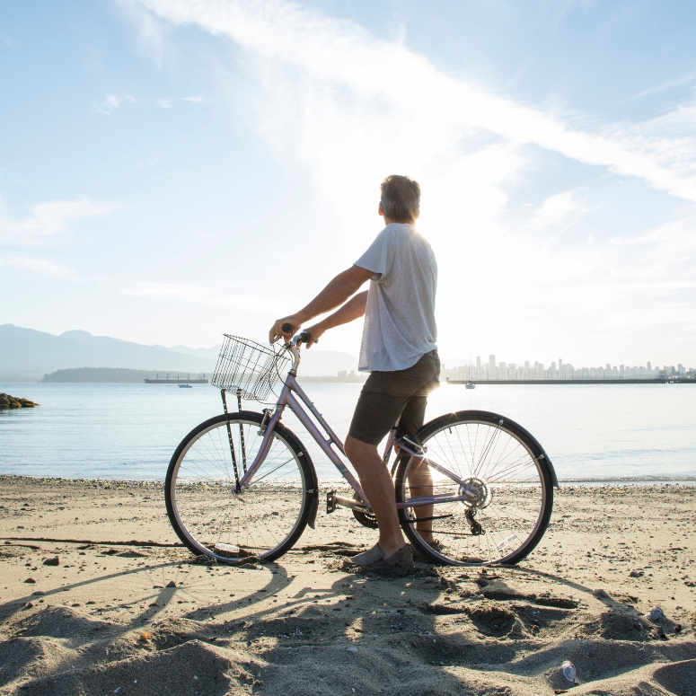 Man-walking-with-bike-on-a-beach-