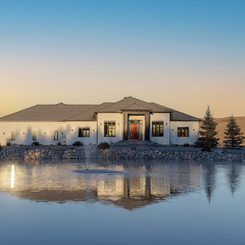 A gorgeous ranch-style gated mansion seen across a still private lake