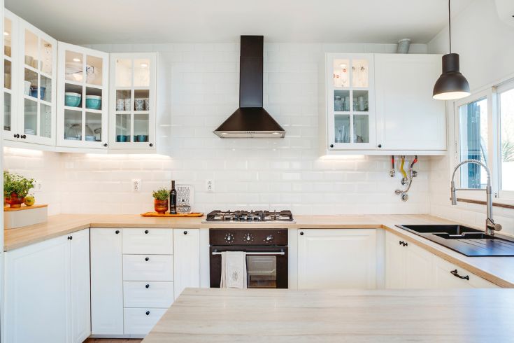 White kitchen tiles with wooden countertop and black oven head 