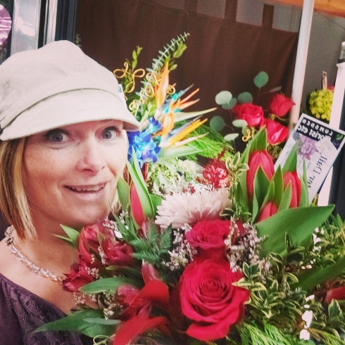 Florist Rachel Brimacombe of Lumsden Florist holding an arrangement with red flowers