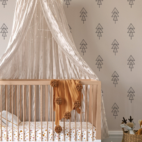 A nursery with wooden crib and a black and white wallpaper with sketched trees