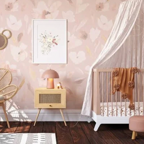 A nursery room with soft pink floral wallpaper