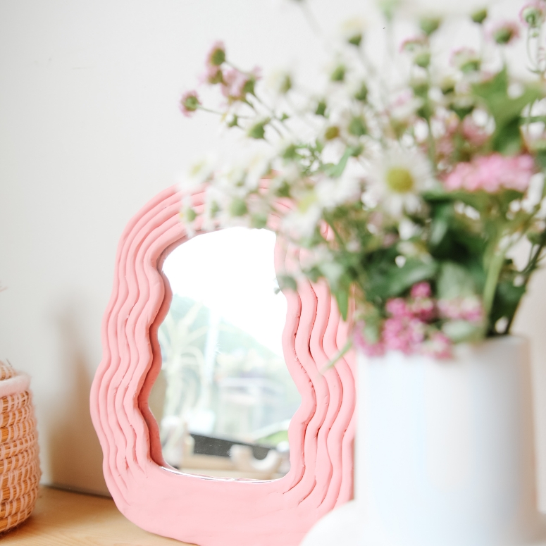 DIY pink mirror on nightstand with flowers beside it